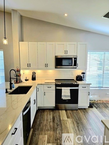 A kitchen with white cabinets and a black stove top oven.