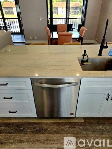 A kitchen with a marble countertop and a stainless steel trash can.