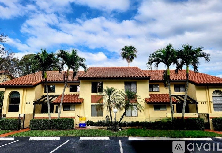 A building with a red tile roof and palm trees in front.