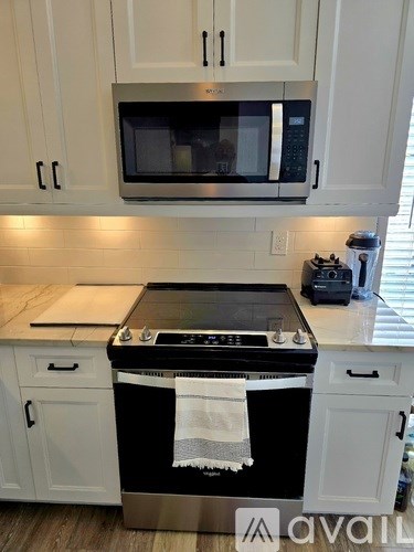 A kitchen with a black stove top oven and white cabinets.
