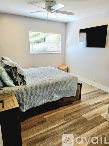 A bedroom with a bed, wooden flooring, and a ceiling fan.