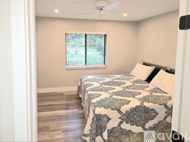 A bedroom with a bed, a window, and a ceiling fan.