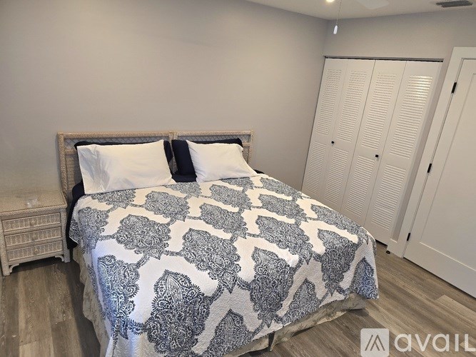 A bed with a patterned comforter and two pillows sits in a room with a wooden headboard and a nightstand.