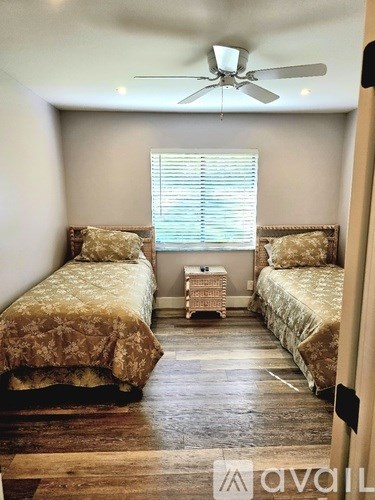 A bedroom with two beds and a ceiling fan.