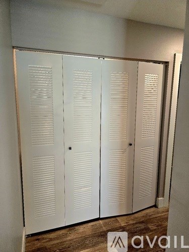 Closet with four doors and a wooden floor.