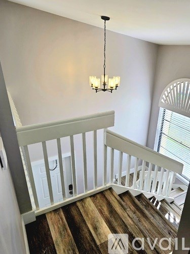 A chandelier hangs over a staircase with wooden steps.