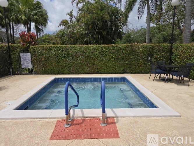 A pool surrounded by a hedge and palm trees.