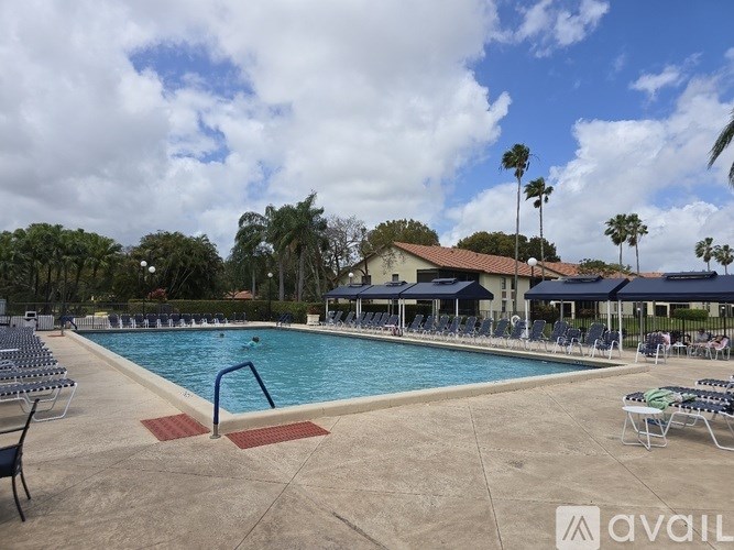 A pool with chairs around it and a building in the background.