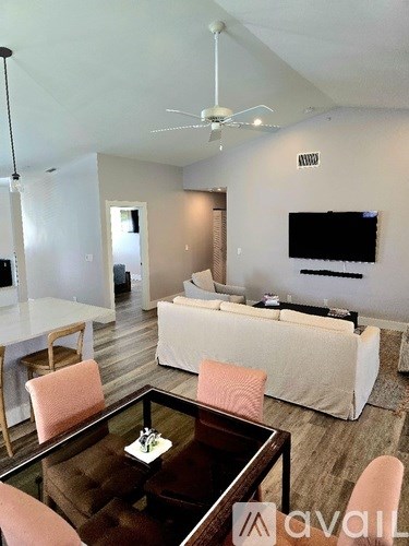 A living room with a white couch, a brown coffee table, and a flat screen TV mounted on the wall.