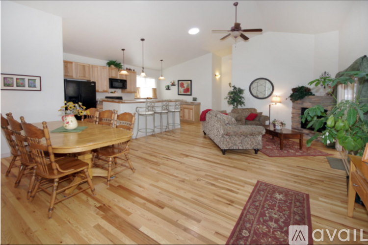 A living room with a wooden floor and a dining table with chairs.