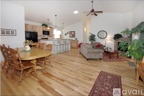 A living room with a wooden floor and a dining table with chairs.