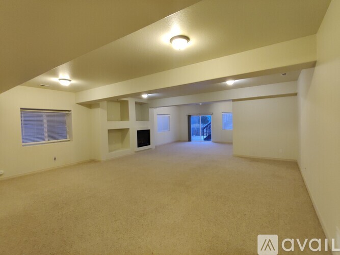 A spacious room with beige carpeting and white walls is available for rent.