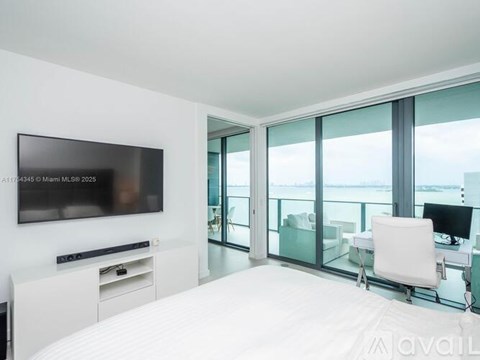 A modern bedroom with a large bed and a flat screen TV mounted on the wall.