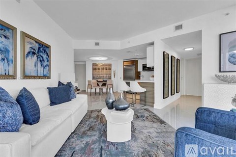 A living room with a white couch and blue pillows.