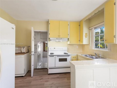 A kitchen with yellow cabinets and white appliances.
