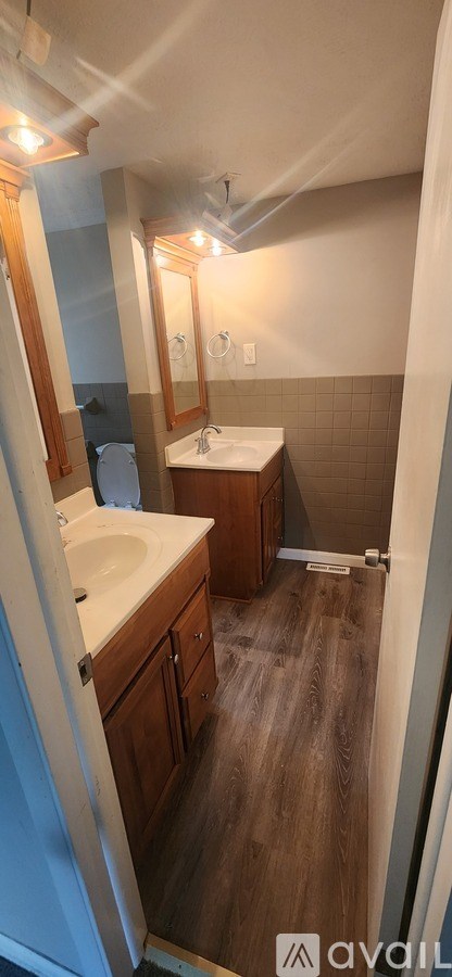 A bathroom with a white sink and brown wood cabinets.