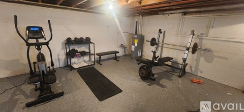 A gym with a treadmill, weights, and a bench.