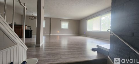 A spacious living room with wooden floors and a staircase on the left side.