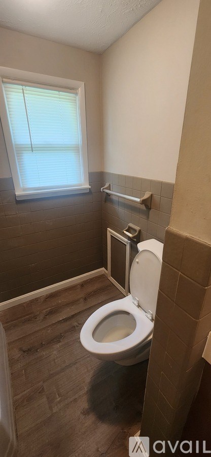 A bathroom with a toilet and a window.