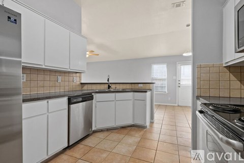 A kitchen with white cabinets and a tiled floor.