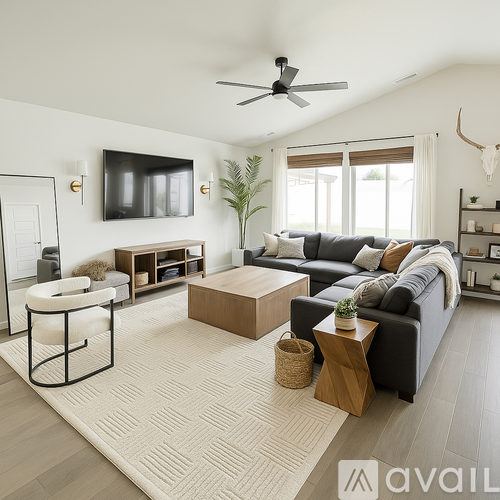 A living room with a black couch, a white chair, a wooden coffee table, and a flat-screen TV mounted on the wall.
