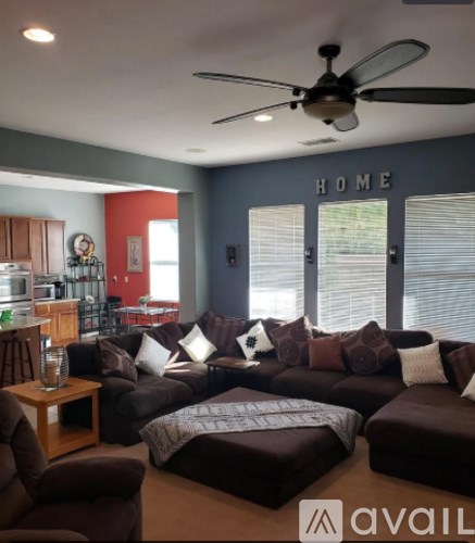 A living room with a brown couch and a ceiling fan.