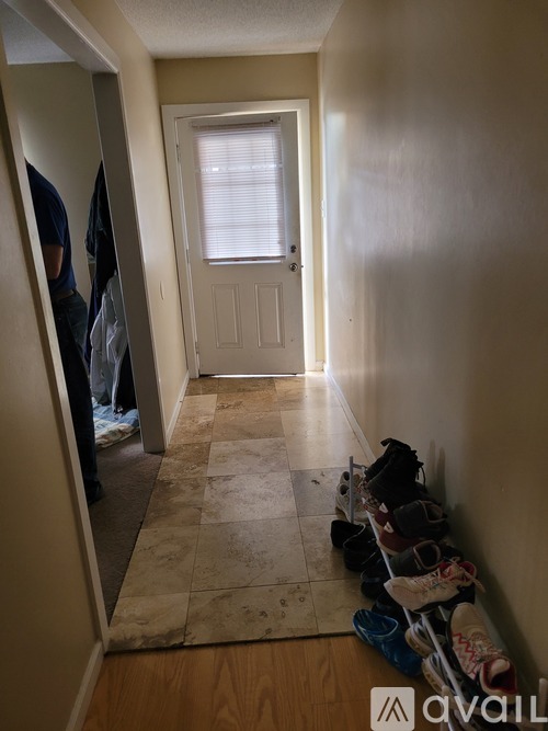 A hallway with a door and shoes lined up on the floor.