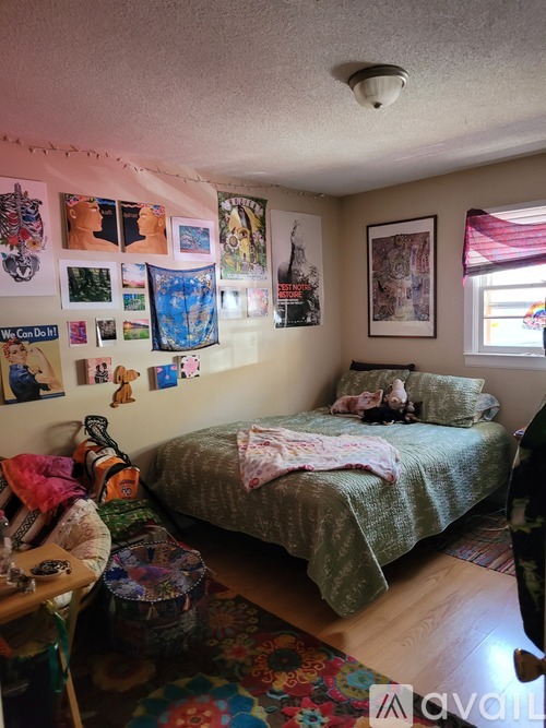 A bedroom with a bed, a table, and pictures on the wall.