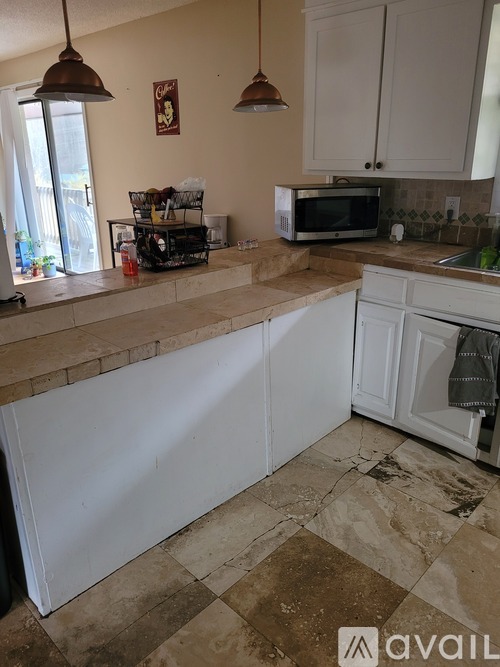 A kitchen with a white counter and a microwave on the counter.