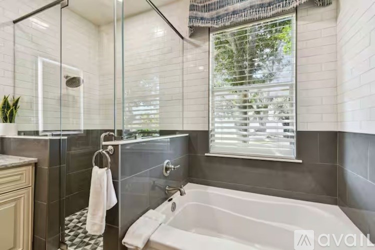 A modern bathroom with a glass shower enclosure and a white bathtub.