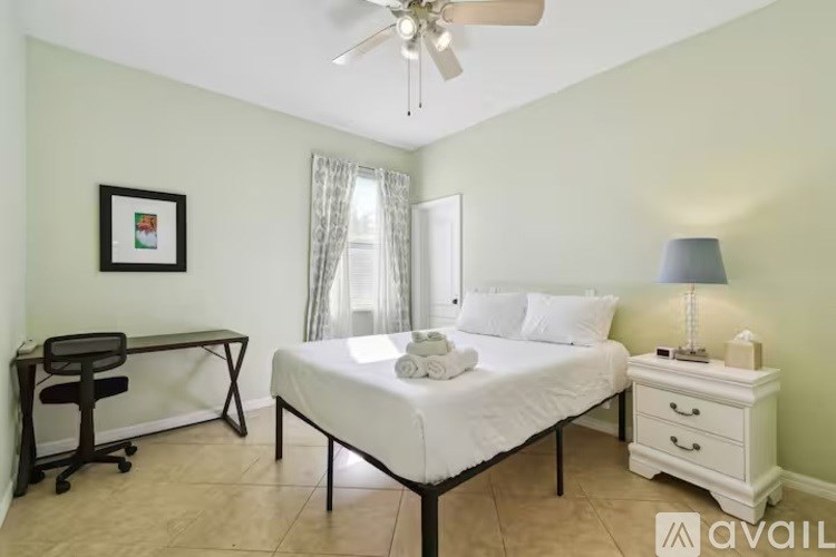 A bedroom with a bed, desk, and chair.