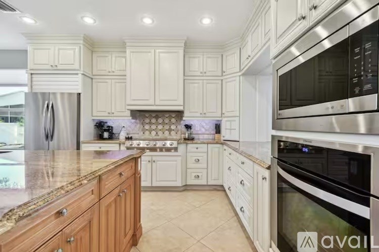 A kitchen with white cabinets and a granite countertop.