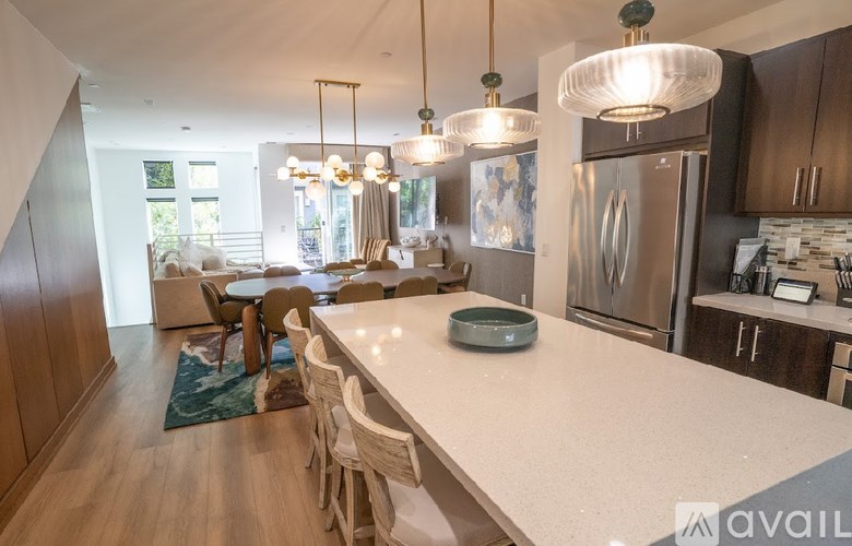A kitchen with a large island and a dining table with chairs.