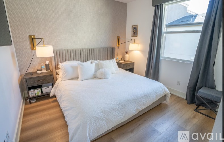 A bedroom with a large bed and two lamps on either side of the bed.