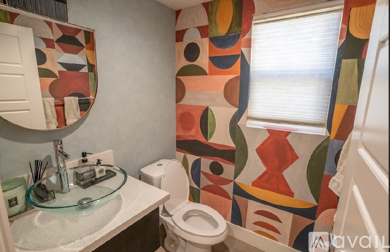 A bathroom with a toilet, sink, mirror, and a colorful shower curtain.