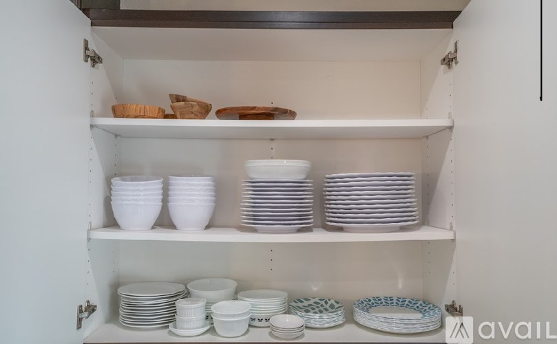 A kitchen cabinet with white plates and bowls on the shelves.