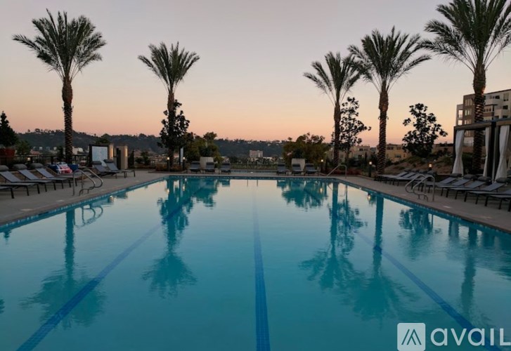 A pool surrounded by palm trees at dusk.
