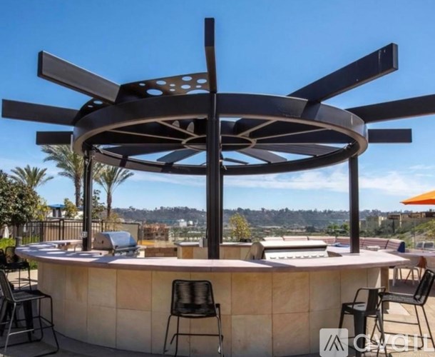 A round outdoor table with a black metal umbrella.