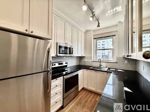 A modern kitchen with a stainless steel refrigerator and black countertops.