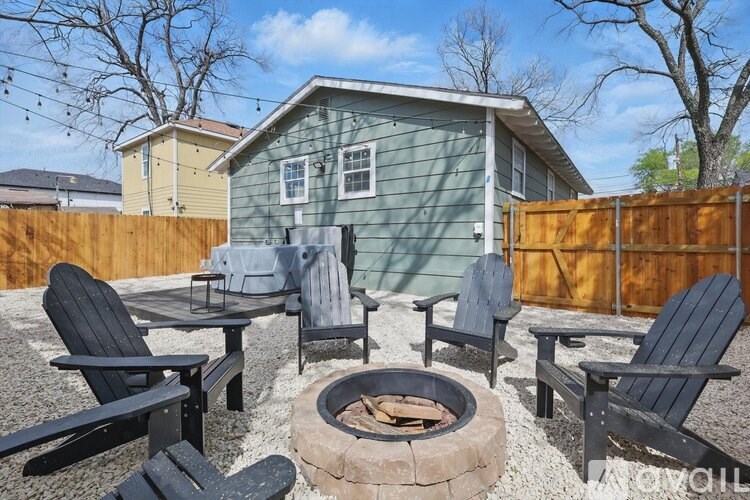 A backyard with a fire pit and chairs.