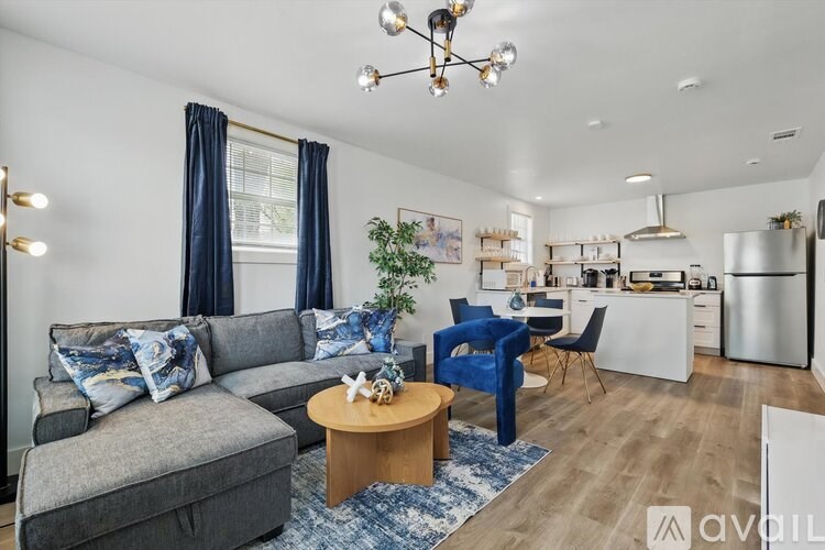 A living room with a grey couch, blue chairs, and a wooden coffee table.