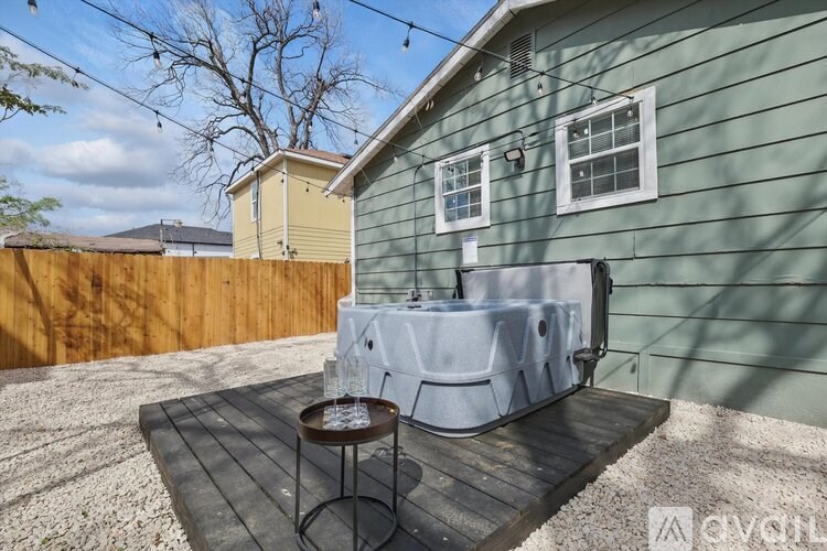 A hot tub sits on a wooden deck in a backyard.