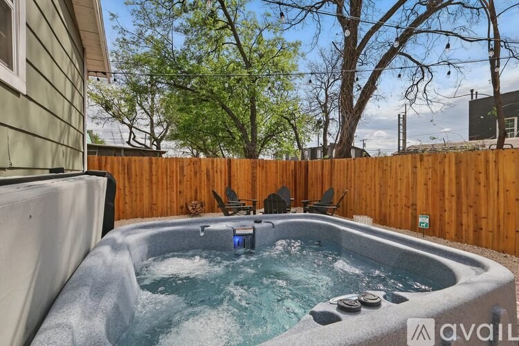 A hot tub in a backyard surrounded by a wooden fence.
