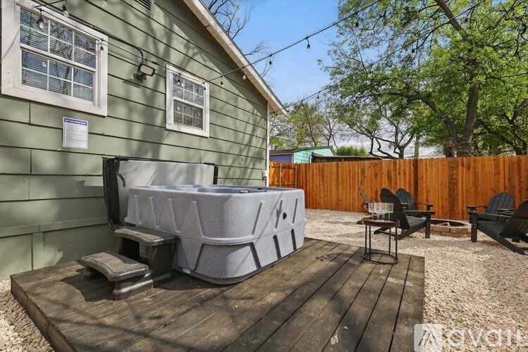 A hot tub sits on a wooden deck in a backyard.