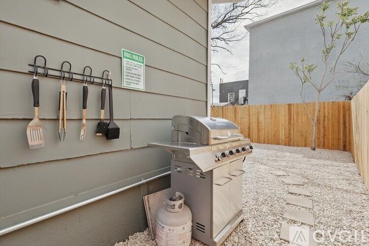 A BBQ grill is on a patio with a sign on the wall.