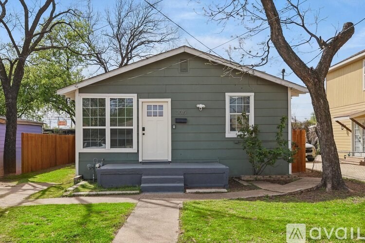A small house with a white door and a tree in front.