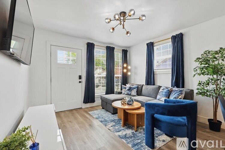 A living room with a blue armchair, a grey sofa, a wooden coffee table, and a television.
