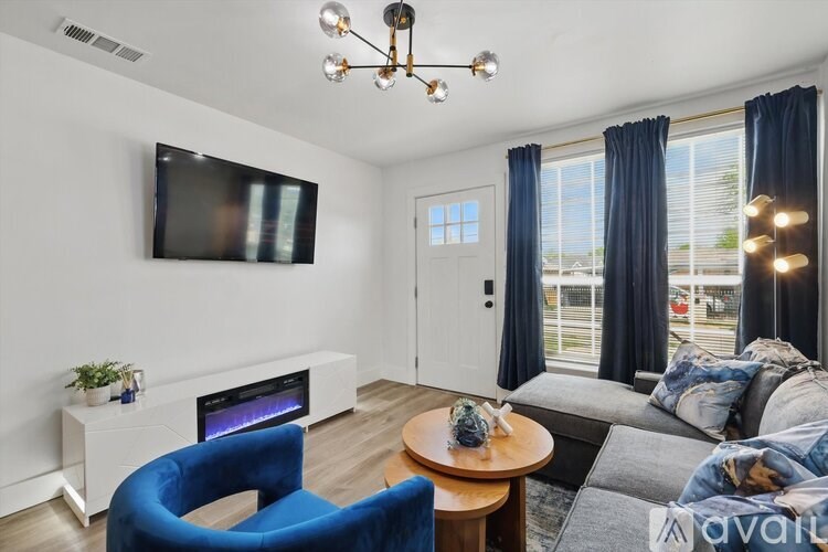 A living room with a blue chair and a television mounted on the wall.