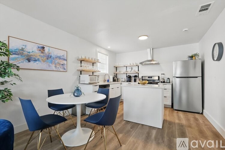 A kitchen with a white table and blue chairs.