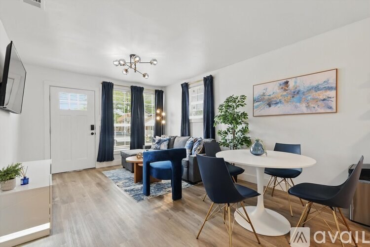 A living room with a blue sofa, a white table, and a painting on the wall.